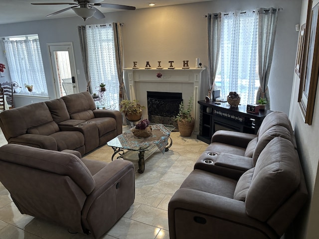 living room with ceiling fan, plenty of natural light, and a tile fireplace