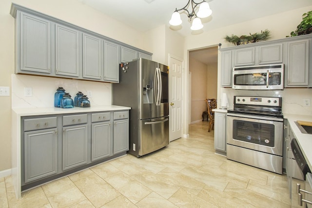 kitchen with pendant lighting, gray cabinets, stainless steel appliances, and a notable chandelier