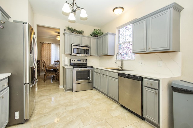 kitchen featuring decorative light fixtures, sink, gray cabinetry, and stainless steel appliances