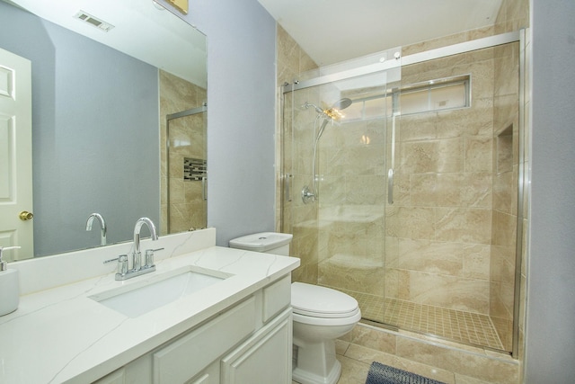 bathroom featuring toilet, vanity, and a shower with shower door