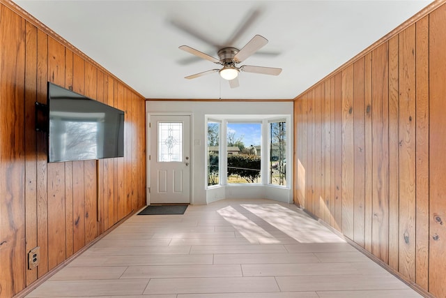 doorway to outside with wooden walls, ceiling fan, light hardwood / wood-style floors, and crown molding