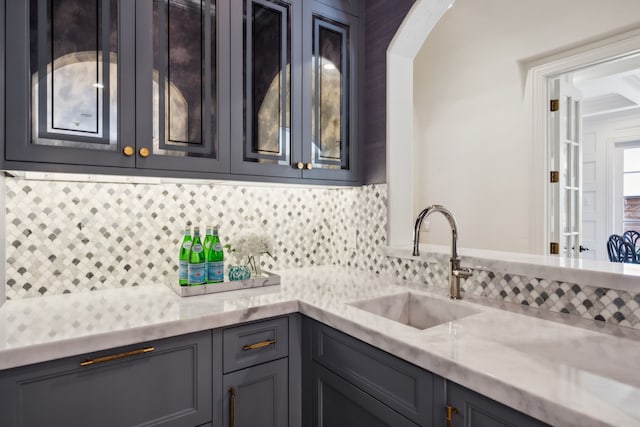 kitchen featuring sink, light stone counters, and backsplash