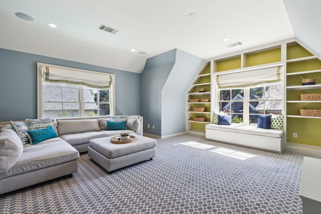 living room featuring lofted ceiling, built in shelves, and carpet