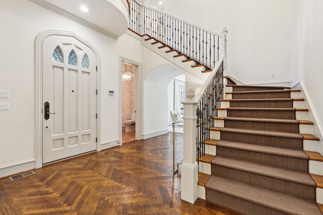 foyer with dark parquet floors and crown molding