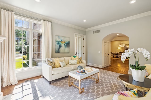 living room with an inviting chandelier, a wealth of natural light, and crown molding