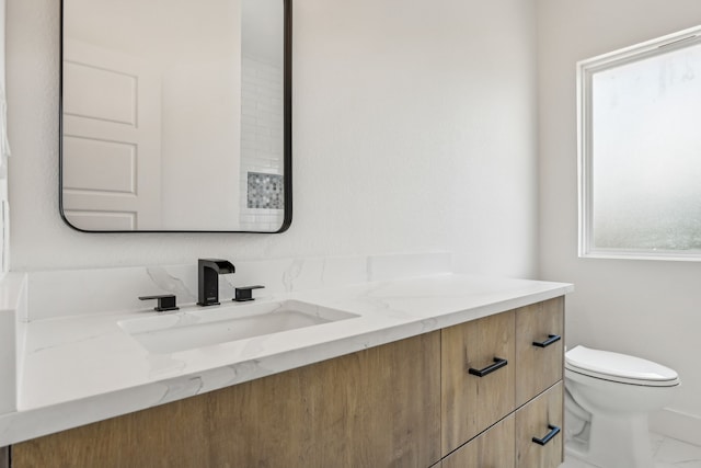 bathroom with a healthy amount of sunlight, vanity, and toilet