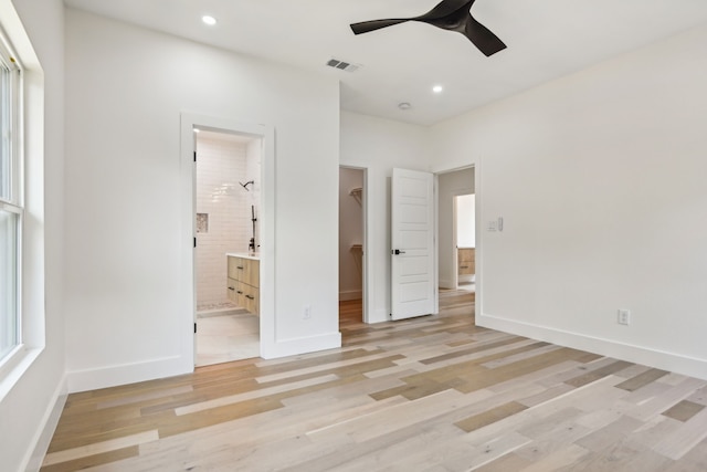 unfurnished bedroom featuring connected bathroom, a closet, light hardwood / wood-style floors, ceiling fan, and a spacious closet