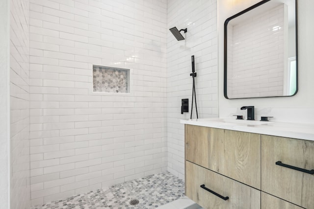 bathroom with tiled shower and vanity