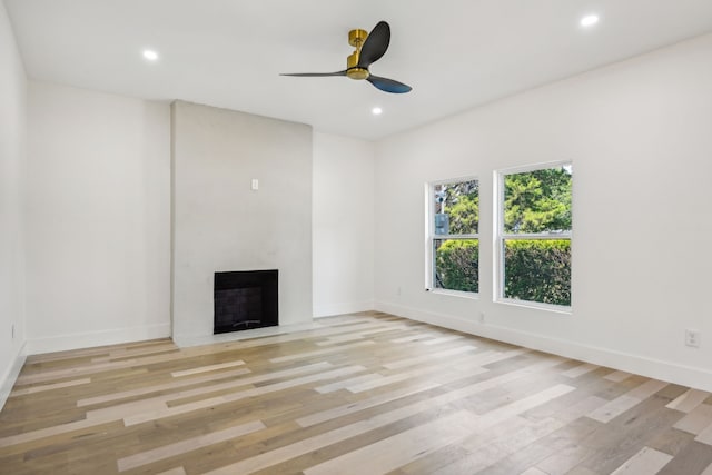 unfurnished living room with a fireplace, light wood-type flooring, and ceiling fan