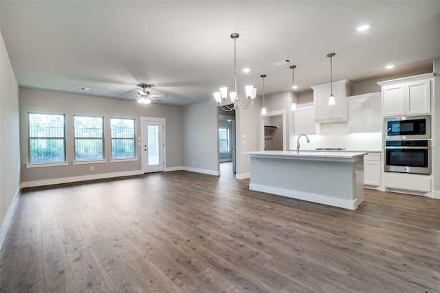 kitchen featuring white cabinetry, stainless steel oven, an island with sink, and built in microwave