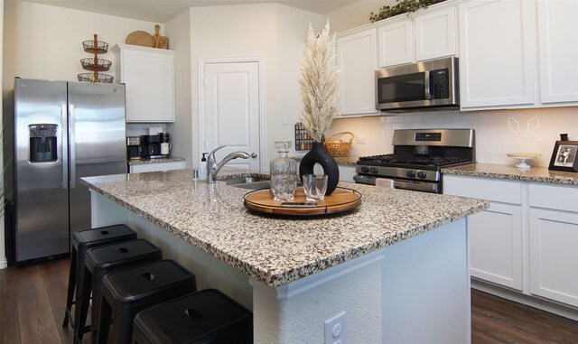 kitchen with a breakfast bar area, stainless steel appliances, and white cabinets