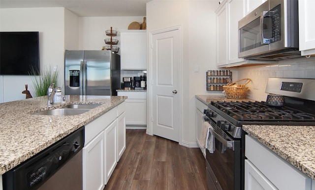 kitchen featuring stainless steel appliances, light stone counters, white cabinets, and dark hardwood / wood-style flooring