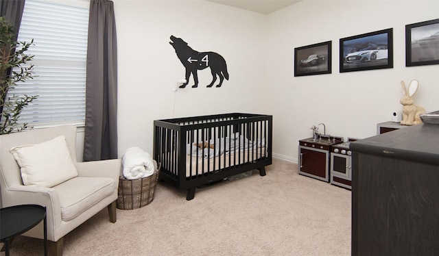 bedroom with light colored carpet and a nursery area