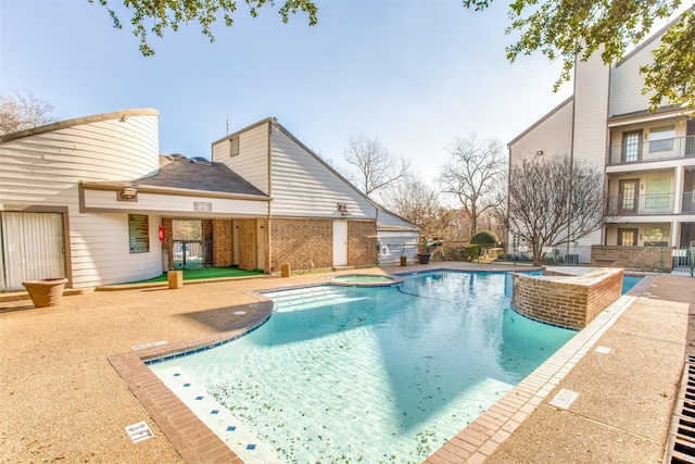 view of swimming pool featuring a hot tub and a patio