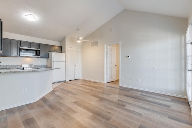 kitchen featuring white fridge, light hardwood / wood-style floors, ceiling fan, high vaulted ceiling, and light stone counters