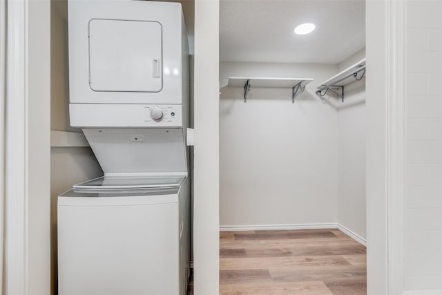 washroom featuring light hardwood / wood-style floors and stacked washing maching and dryer