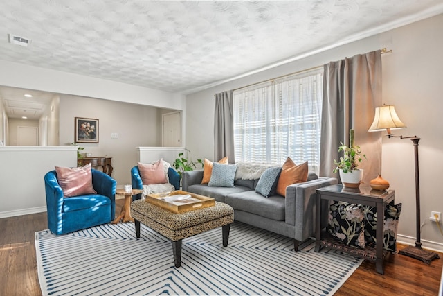 living area featuring baseboards, a textured ceiling, visible vents, and wood finished floors