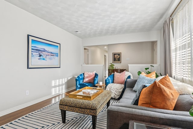 living area featuring visible vents, a textured ceiling, baseboards, and wood finished floors