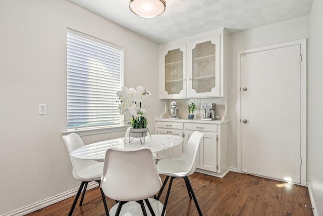 dining space with baseboards and dark wood-type flooring