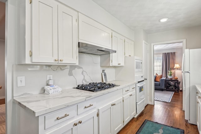 kitchen with light stone counters, dark wood-type flooring, white cabinets, white appliances, and under cabinet range hood