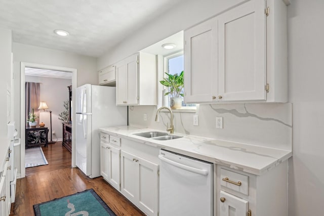 kitchen with light stone counters, white appliances, a sink, and white cabinetry