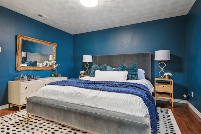 bedroom with visible vents, baseboards, and wood finished floors