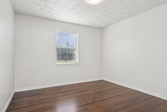 spare room featuring baseboards and wood finished floors