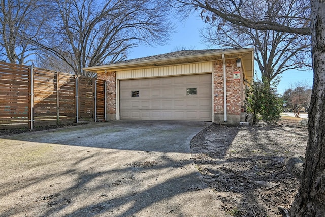 garage featuring fence and concrete driveway