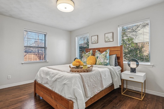 bedroom with multiple windows, baseboards, and wood finished floors