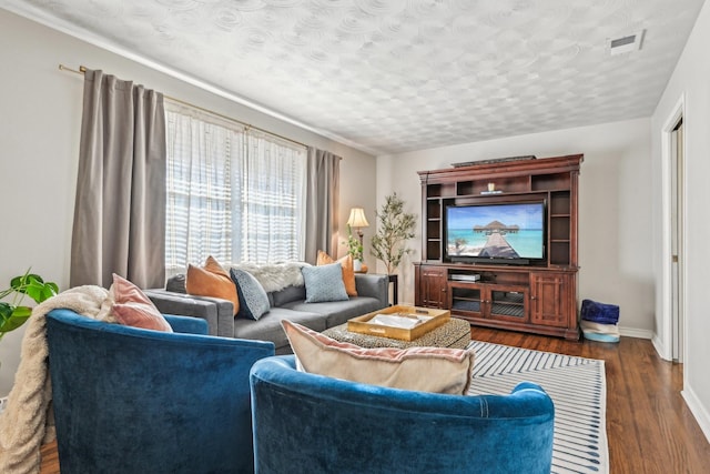 living area featuring a textured ceiling, wood finished floors, visible vents, and baseboards