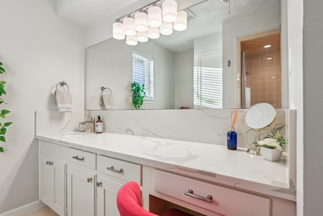 bathroom featuring baseboards, a tile shower, and vanity