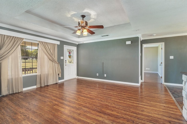 spare room featuring dark wood-type flooring, ceiling fan, a tray ceiling, and ornamental molding