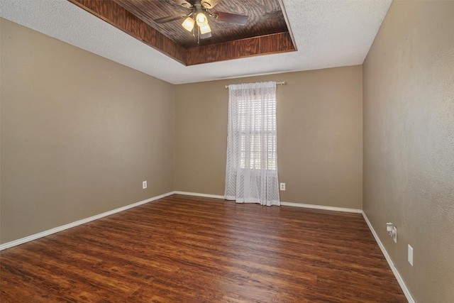 unfurnished room featuring a raised ceiling, ceiling fan, a textured ceiling, and dark hardwood / wood-style flooring