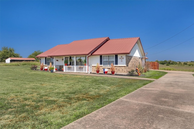 view of front of home with covered porch, metal roof, a front lawn, and brick siding