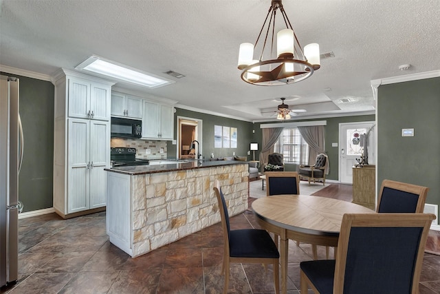 kitchen with ceiling fan with notable chandelier, a sink, backsplash, black appliances, and dark countertops