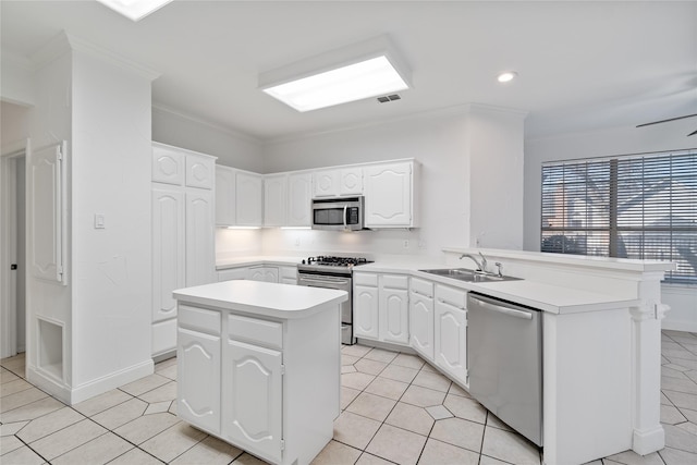 kitchen with sink, stainless steel appliances, white cabinetry, and a center island