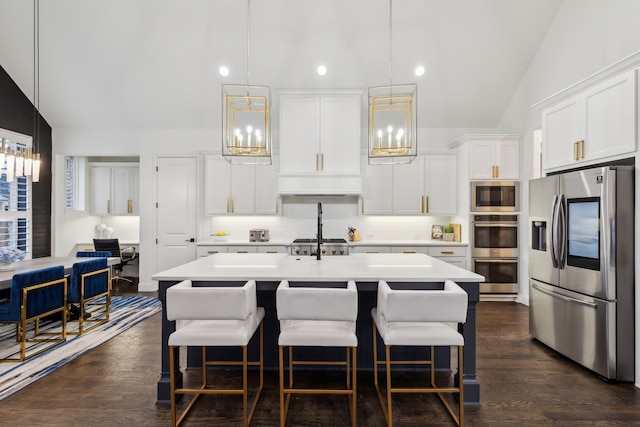 kitchen with a center island with sink, hanging light fixtures, appliances with stainless steel finishes, decorative backsplash, and white cabinets