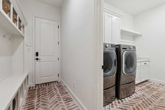 clothes washing area featuring washing machine and dryer and cabinets