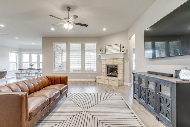 living room with ceiling fan, light wood-type flooring, and a fireplace