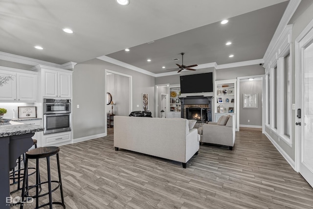 living room featuring light hardwood / wood-style floors, ceiling fan, and crown molding