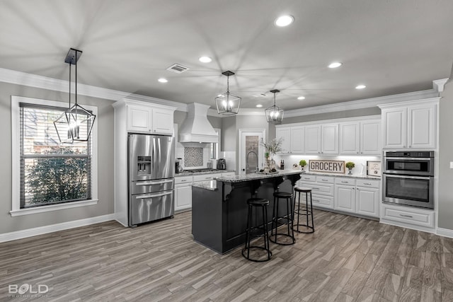 kitchen featuring stainless steel appliances, a center island with sink, custom range hood, and white cabinetry