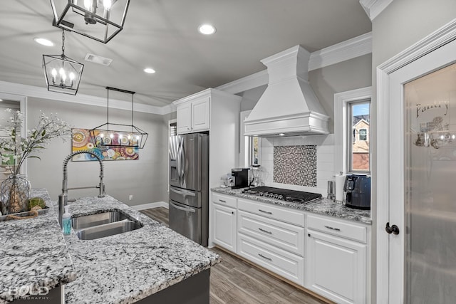 kitchen featuring hanging light fixtures, stainless steel appliances, premium range hood, white cabinets, and sink