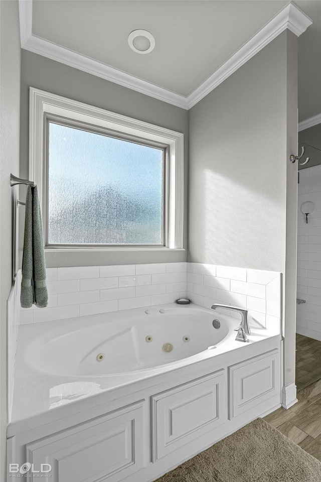 bathroom with wood-type flooring, ornamental molding, and a bathing tub