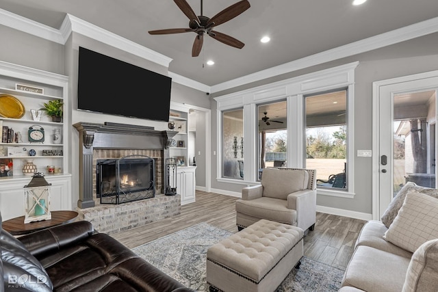 living room featuring a brick fireplace, light wood-type flooring, and crown molding