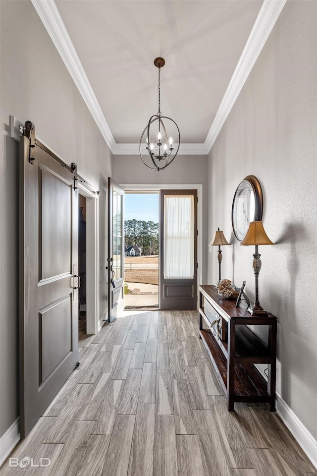 entryway with a chandelier, crown molding, and a barn door