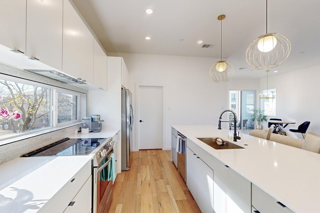 kitchen featuring stainless steel appliances, white cabinets, sink, and pendant lighting