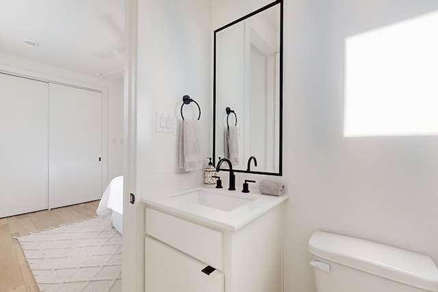 bathroom featuring toilet, wood-type flooring, and vanity