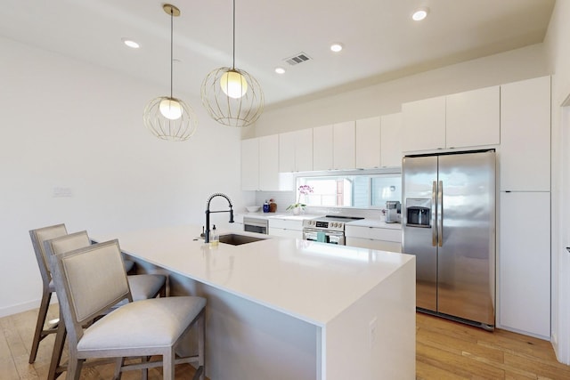 kitchen with decorative light fixtures, a center island with sink, appliances with stainless steel finishes, and sink