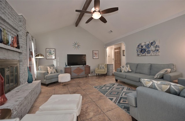 tiled living room featuring a brick fireplace, ceiling fan, and vaulted ceiling with beams