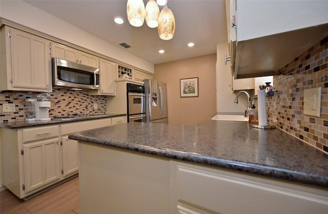 kitchen with kitchen peninsula, decorative light fixtures, stainless steel appliances, decorative backsplash, and sink